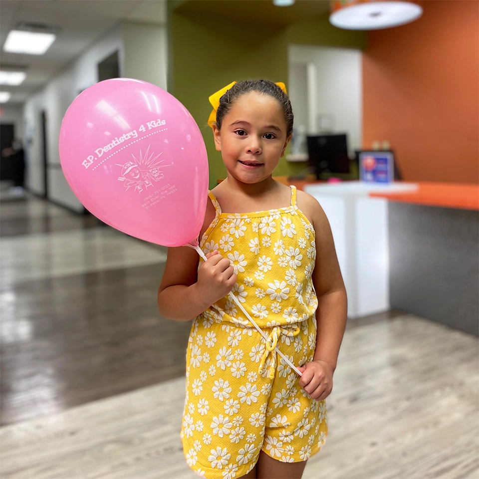 Child holding a balloon in a dentists office